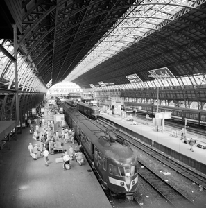 881969 Gezicht op de perrons onder de eerste perronkap van het N.S.-station Amsterdam C.S. te Amsterdam, met op de ...